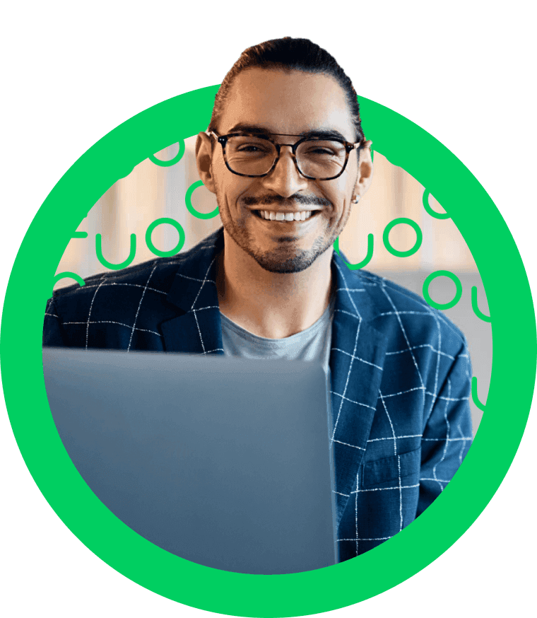 Hombre joven con gafas y saco a cuadros sonriendo frente a laptop, fondo con círculos verdes